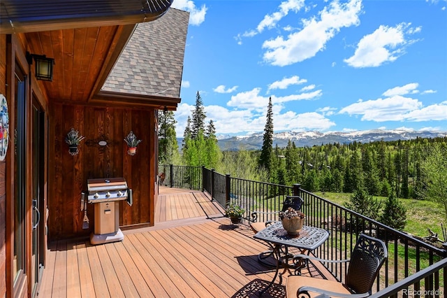 wooden deck featuring a grill, a mountain view, and a forest view