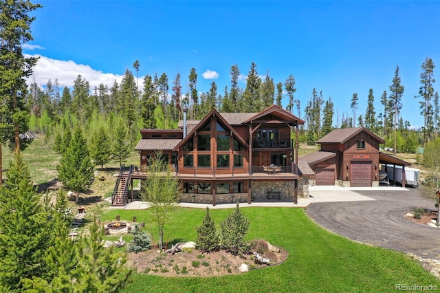 view of front of house with a fire pit, stairway, a front yard, a garage, and stone siding