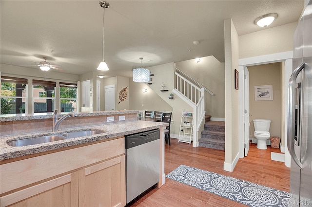 kitchen with light brown cabinets, hanging light fixtures, sink, ceiling fan, and appliances with stainless steel finishes