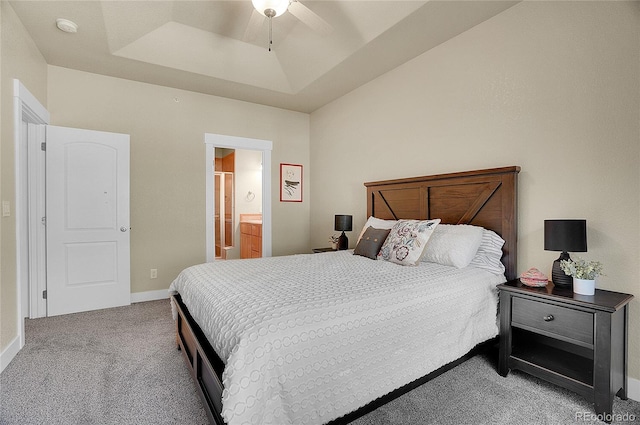 carpeted bedroom featuring ensuite bath, ceiling fan, and a tray ceiling