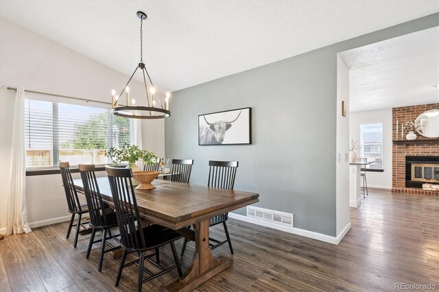 700 Prairie Ridge Rd, Highlands Ranch, CO 80126 - dining room featuring dark wood-style flooring, a chandelier, a brick fireplace, and vaulted ceiling