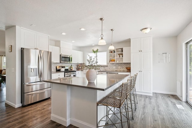 700 Prairie Ridge Rd, Highlands Ranch, CO 80126 - kitchen featuring appliances with stainless steel finishes, wood finished floors, tasteful backsplash, open shelves, and recessed lighting