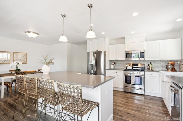 700 Prairie Ridge Rd, Highlands Ranch, CO 80126 - kitchen featuring stainless steel appliances, a kitchen breakfast bar, tasteful backsplash, dark wood-type flooring, and decorative light fixtures