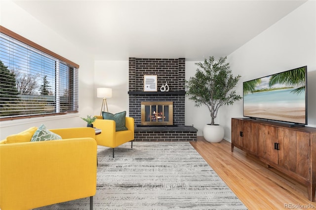 living room featuring wood-type flooring and a brick fireplace