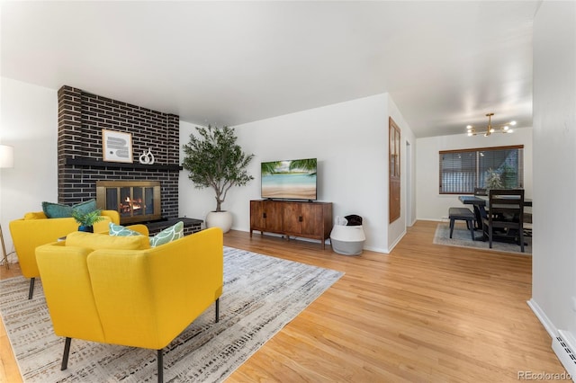 living room featuring a notable chandelier, wood-type flooring, a fireplace, and baseboard heating