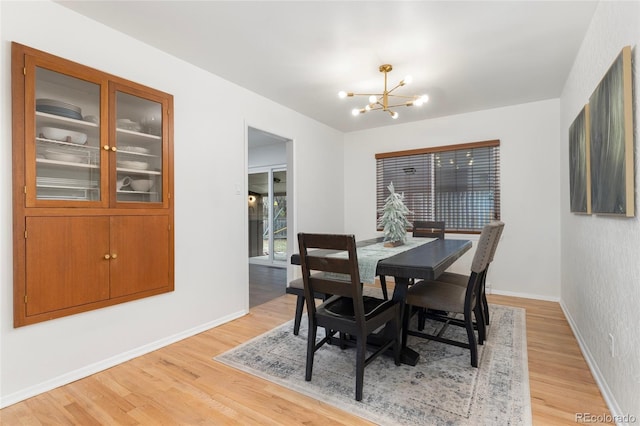 dining room with light hardwood / wood-style floors and an inviting chandelier