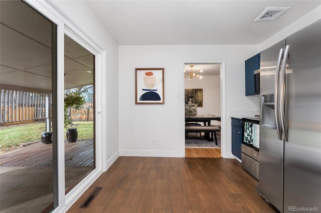 kitchen with blue cabinetry, dark wood-type flooring, a notable chandelier, and appliances with stainless steel finishes