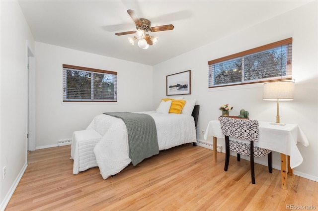 bedroom featuring light hardwood / wood-style flooring, ceiling fan, and a baseboard heating unit