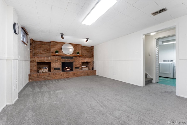 unfurnished living room with a fireplace, carpet floors, and washer / dryer