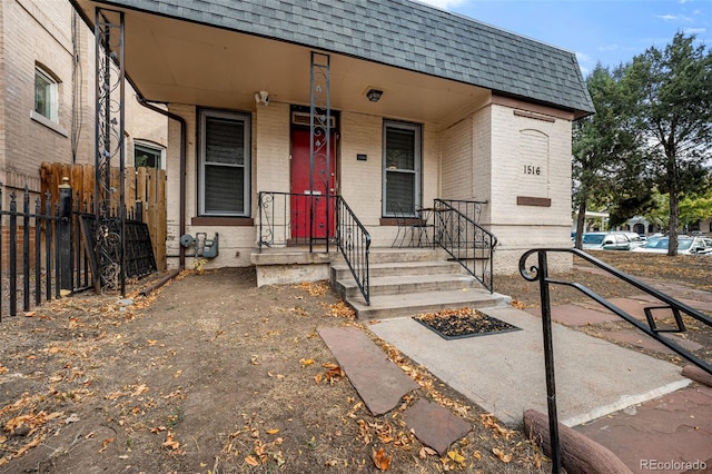 1516 Lafayette St, Denver, CO 80218 - view of front of property featuring roof with shingles, brick siding, mansard roof, fence, and covered porch