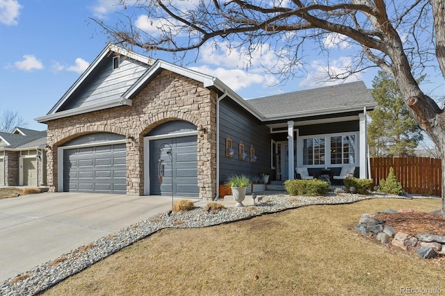 view of front of home with a shingled roof, fence, a garage, stone siding, and driveway