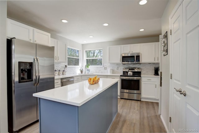 15432 Greenstone Cir, Parker, CO 80134 - kitchen featuring appliances with stainless steel finishes, light wood-type flooring, tasteful backsplash, white cabinetry, and light countertops