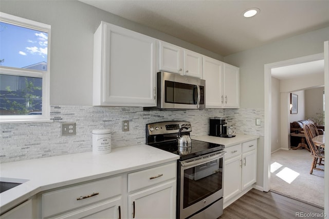 15432 Greenstone Cir, Parker, CO 80134 - kitchen with appliances with stainless steel finishes, white cabinetry, decorative backsplash, light countertops, and wood finished floors