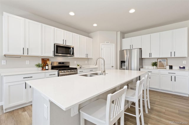 113 Marlowe Dr, Erie, CO 80516 - kitchen with stainless steel appliances, a sink, a kitchen breakfast bar, light wood-style floors, and white cabinets