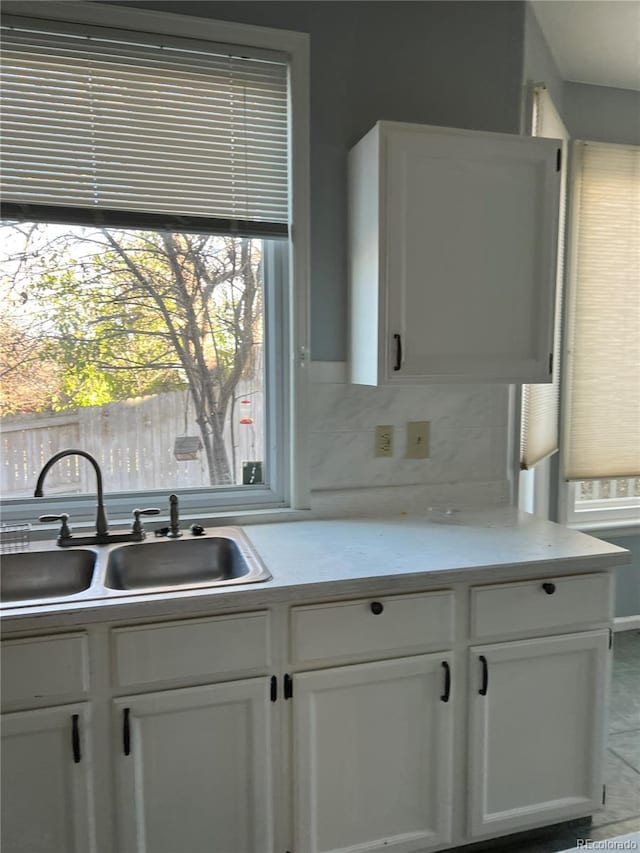 kitchen featuring backsplash, sink, and white cabinets