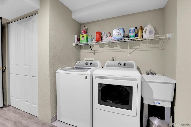 washroom with light hardwood / wood-style floors, washing machine and dryer, and sink