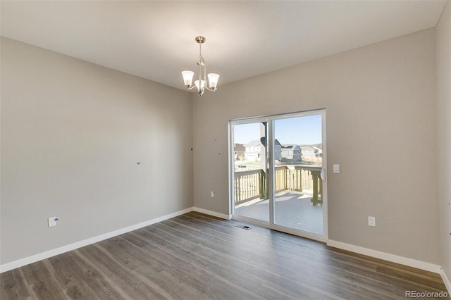 spare room featuring a notable chandelier and dark hardwood / wood-style floors