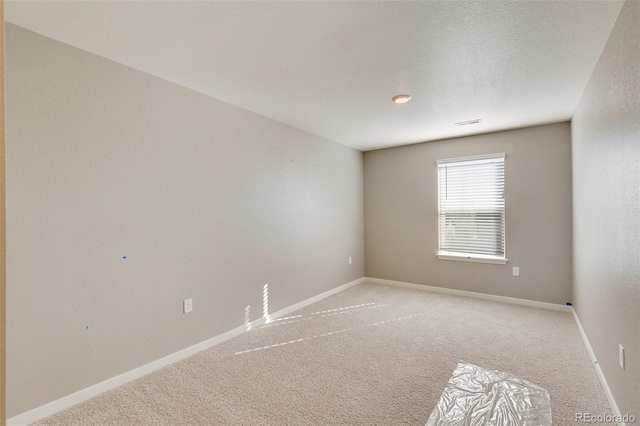 carpeted empty room with a textured ceiling