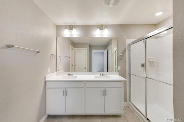 bathroom with a shower with door, vanity, and tile patterned flooring