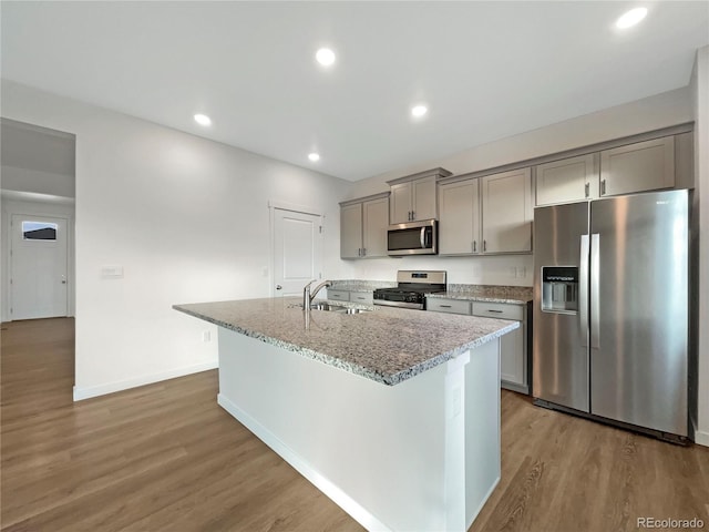 kitchen featuring stainless steel appliances, a center island with sink, sink, and gray cabinetry