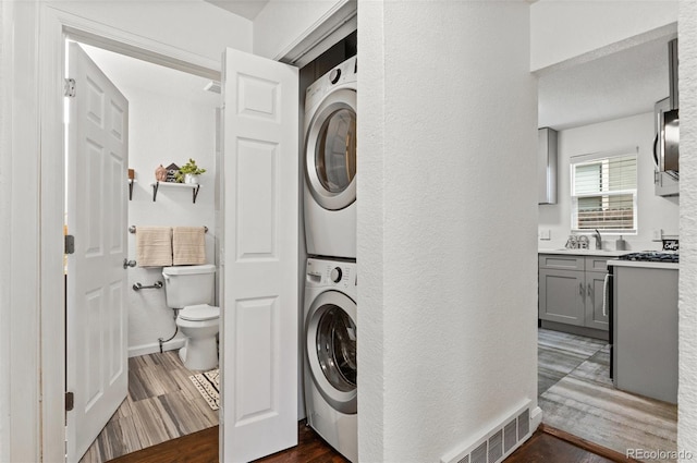 1414 W Nevada Pl, Denver, CO 80223 - laundry room featuring stacked washer / drying machine, dark wood finished floors, and a textured wall