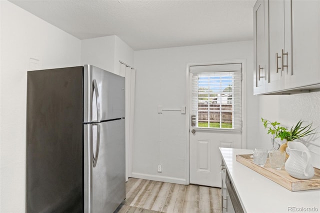 1414 W Nevada Pl, Denver, CO 80223 - kitchen featuring freestanding refrigerator, light wood finished floors, light countertops, baseboards, and white cabinetry