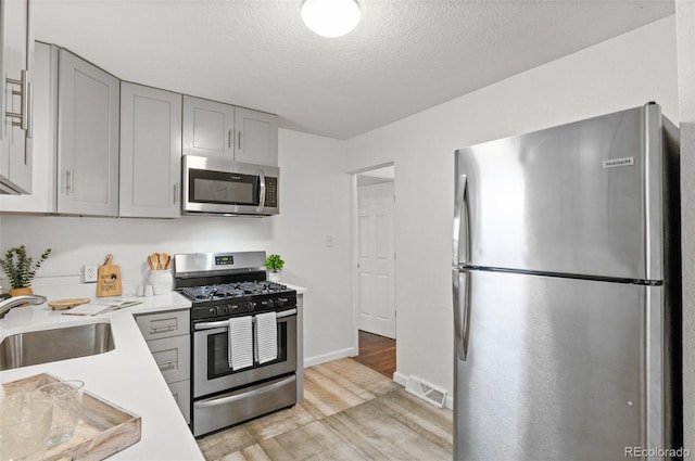 1414 W Nevada Pl, Denver, CO 80223 - kitchen with appliances with stainless steel finishes, a sink, light wood finished floors, gray cabinets, and light countertops