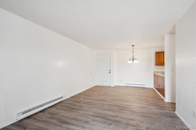 unfurnished dining area featuring baseboard heating, a baseboard radiator, a chandelier, wood finished floors, and a textured ceiling