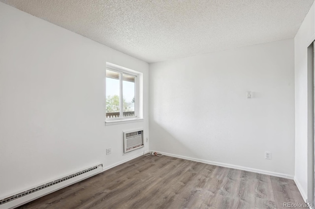unfurnished room with a baseboard radiator, wood finished floors, a wall mounted air conditioner, a textured ceiling, and baseboards