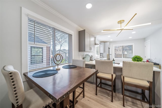 dining area with ornamental molding, light wood-type flooring, and a notable chandelier