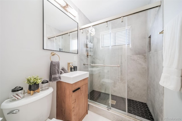 bathroom featuring vanity, toilet, and a shower with door