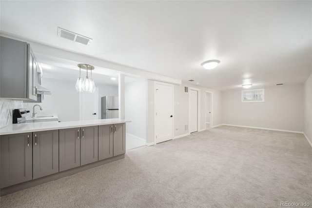 basement with light carpet, stainless steel refrigerator, and sink