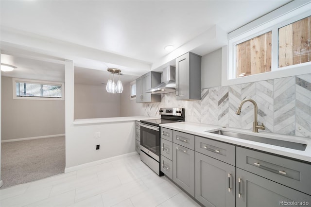 kitchen featuring stainless steel range with electric stovetop, sink, wall chimney exhaust hood, gray cabinets, and decorative light fixtures