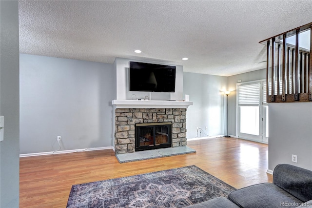 living room with a fireplace, a textured ceiling, and hardwood / wood-style floors