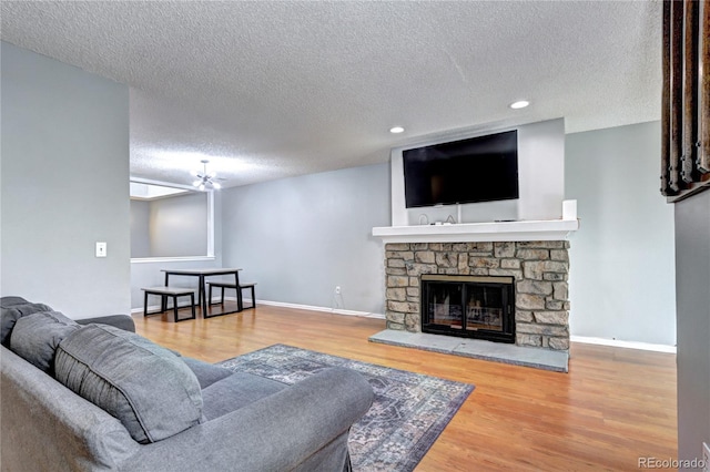 living room with a textured ceiling, ceiling fan, a fireplace, and hardwood / wood-style flooring