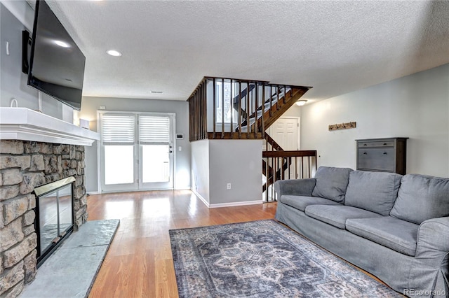 living room featuring a fireplace, a textured ceiling, and hardwood / wood-style flooring