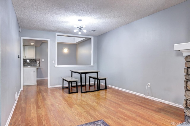 dining space featuring a textured ceiling, a notable chandelier, and light hardwood / wood-style floors