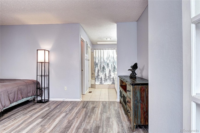 bedroom with a textured ceiling, light hardwood / wood-style flooring, and ensuite bath