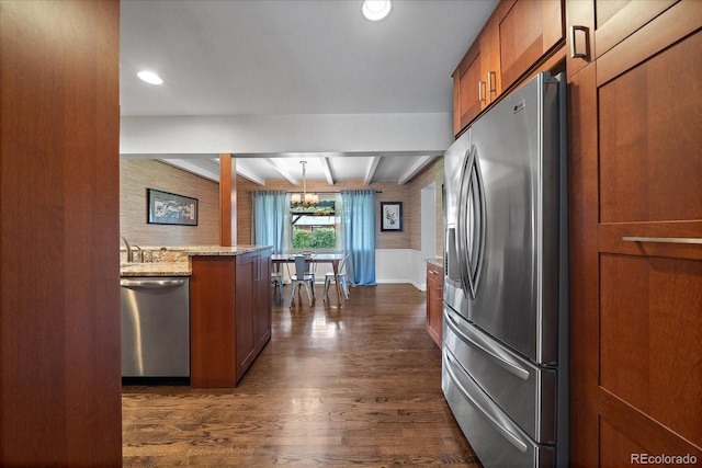 kitchen with light stone counters, a chandelier, decorative light fixtures, stainless steel appliances, and beam ceiling