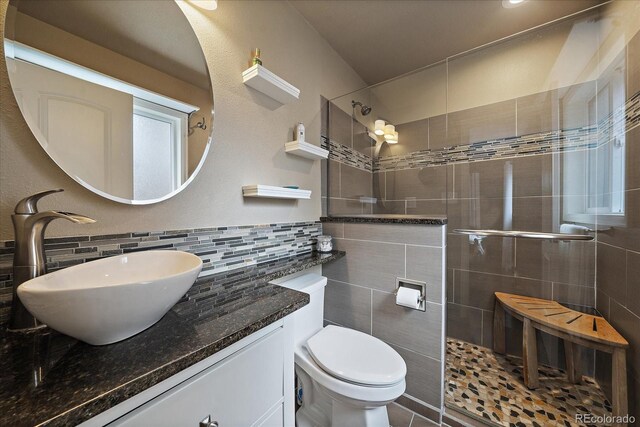 bathroom featuring tiled shower, vanity, decorative backsplash, and toilet