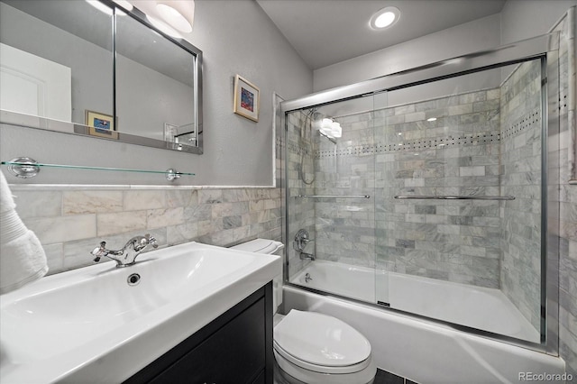 full bathroom with tile walls, toilet, vanity, and combined bath / shower with glass door