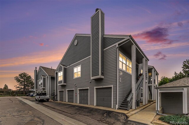 7453 Singing Hills Dr Unit E105, Boulder, CO 80301 - property exterior at dusk featuring a chimney, stairway, and a garage