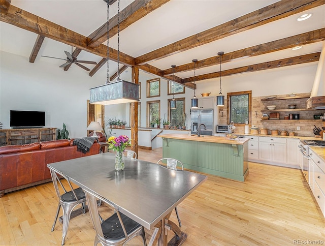 dining space featuring beam ceiling, sink, ceiling fan, and light hardwood / wood-style flooring