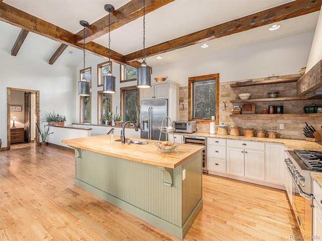 kitchen with light hardwood / wood-style flooring, beverage cooler, a center island with sink, high end appliances, and a kitchen bar