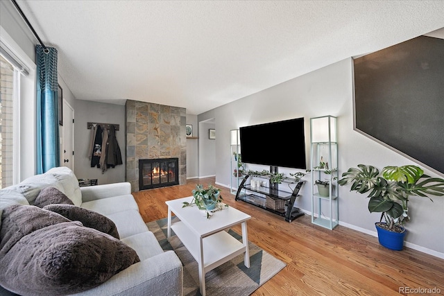 living room featuring a textured ceiling, light hardwood / wood-style floors, and a fireplace