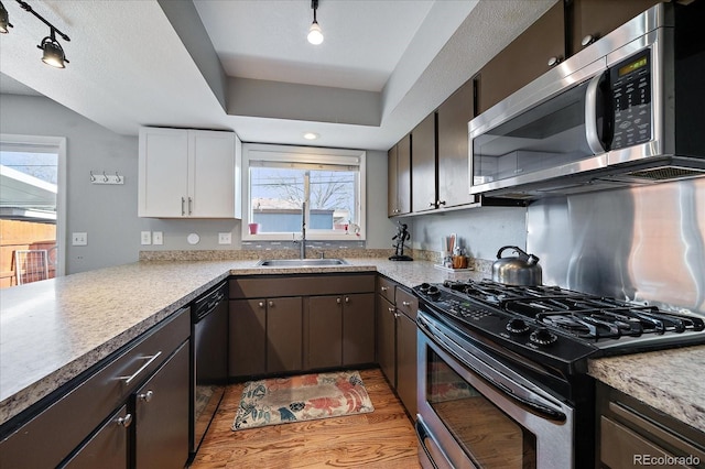 kitchen featuring rail lighting, sink, appliances with stainless steel finishes, dark brown cabinets, and white cabinetry