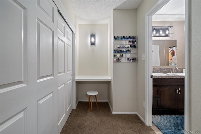 hall featuring carpet, sink, and a textured ceiling