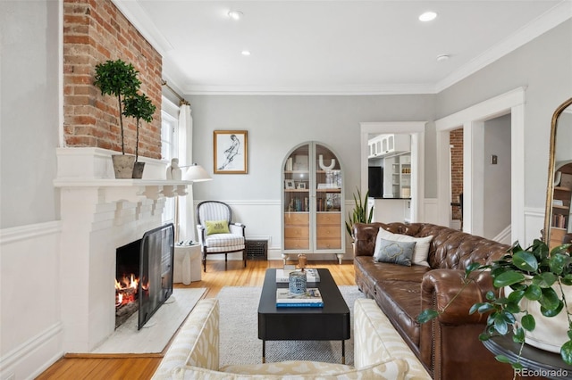 living room with crown molding, light hardwood / wood-style floors, and a large fireplace