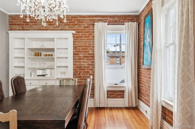 unfurnished dining area with ornamental molding, brick wall, and light hardwood / wood-style flooring