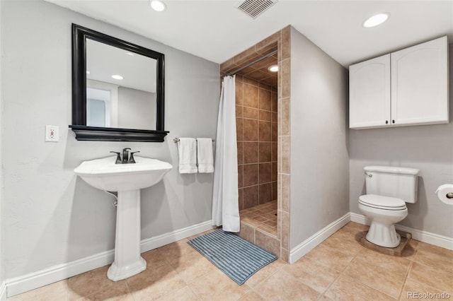 bathroom with toilet, curtained shower, and tile patterned flooring